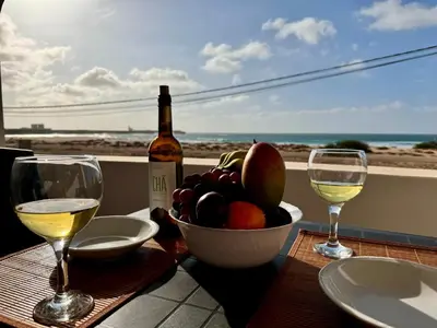 a table with a bowl of fruit and two glasses of wine at Sea view - Ca Mauro - Praia Cabral - Wi-Fi in Sal Rei