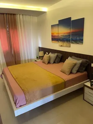 a bedroom with a large bed with two paintings on the wall at Chez Lena, Appartement confortable 3 chambres in Praia