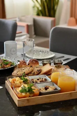 a tray of food on a table with orange juice at Chez Lena, Appartement confortable 3 chambres in Praia