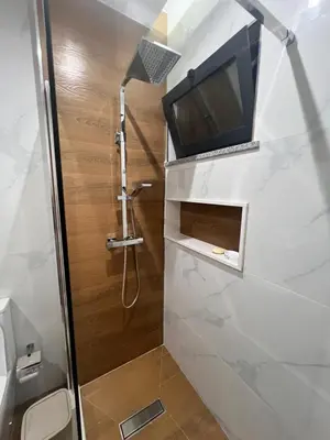 a bathroom with a shower with a tv on the wall at Ondas Relax House in Praia
