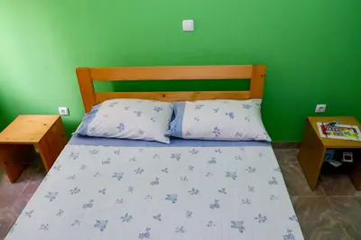 a bedroom with a bed with a green wall at FADIAS Quartos - Rooms in Ribeira Grande