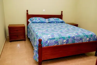 a bed with a blue and white comforter and a night stand at FADIAS Quartos - Rooms in Ribeira Grande