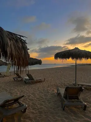 two chairs and umbrellas on the beach at sunset at FantaSea Apartment Leme Bedje in Santa Maria