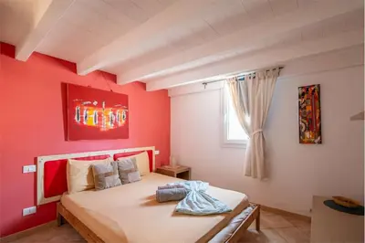 a bedroom with a bed with red walls and a window at Attico Residence Costa do Sol in Sal Rei