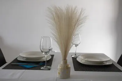 a table with plates and glasses and a vase with grass at APARTAMENTO T2 - SAL REI - Boa Vista in Sal Rei