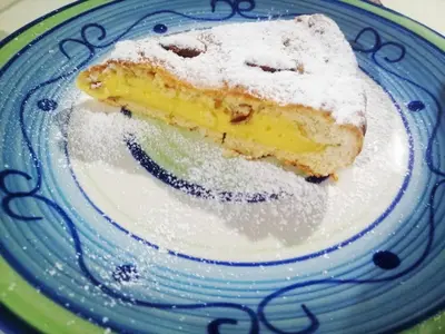 a piece of cake on a plate with powdered sugar at Pensão Big Game Maio Vila do Maio in Vila do Maio