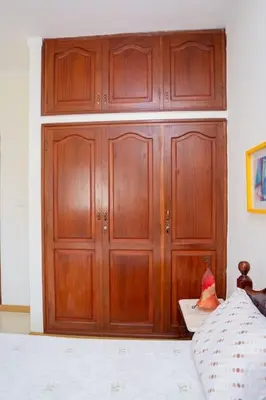 a large wooden cabinet in a bedroom with a bed at Bungavília house, Palmarejo in Praia