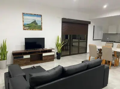 a living room with a black couch and a television at Casa Nelly & Toi JB in Tarrafal