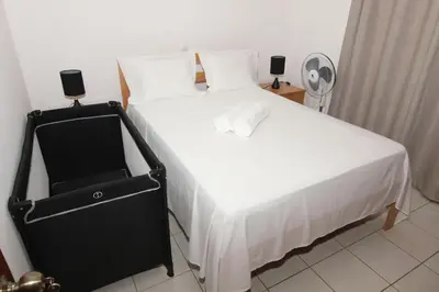 a bedroom with a large white bed with two speakers at Kasa Tabuga in Porto Novo