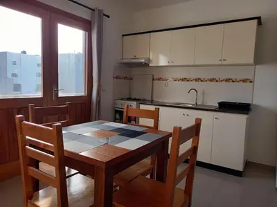 a kitchen with a wooden table and chairs and a kitchen with white cabinets at One cozy bedroom - Studio in Santa Maria in Santa Maria