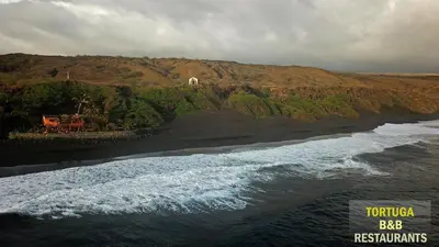 an aerial view of a black beach with the ocean at Tortuga B&B in São Filipe