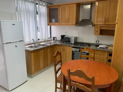 a kitchen with a table and a white refrigerator at Kaza Awa - Urban Guesthouse in Praia