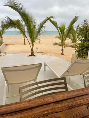 two chairs and a table on a beach with palm trees at Villa Alfredo Marchetti 13B in Cabeçadas