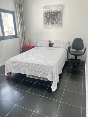 a bedroom with two beds and a chair at Apto Duarte quarto no terraço in Praia