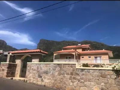 a house on a stone wall with a mountain in the background at Conforto ,Natureza e Relaxamento in Carvoeiros