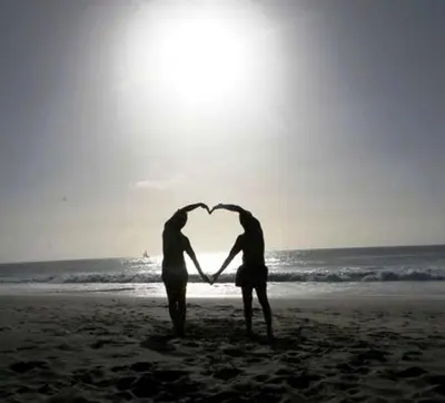 two people standing on the beach forming a heart at Casa Bahia 4 in Santa Maria
