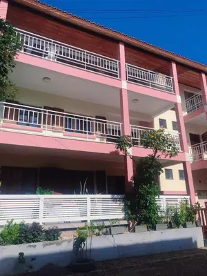 a pink and white building with balconies and trees at Conforto no Coração do Tarrafal in Tarrafal