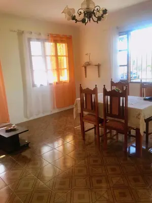 a dining room with a table and chairs and windows at Conforto no Coração do Tarrafal in Tarrafal