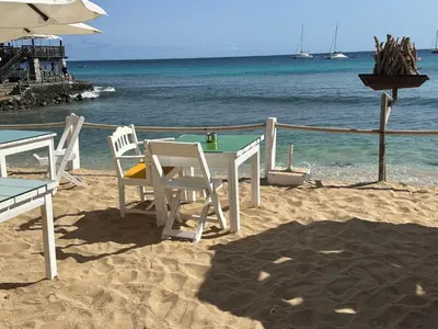 a table and chairs on a beach with the ocean at Porto Antigo 2 studio 15 beach and pool in Santa Maria