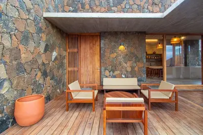 a patio with chairs and a table and a stone wall at Villa, Vue Mer et Piscine Privée in Mindelo