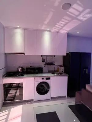 a kitchen with white cabinets and a washing machine at Alojamento Ribeirinha in Mindelo