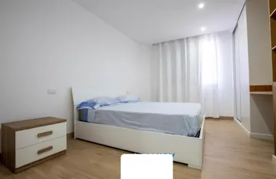 a white bedroom with a bed and a dresser at Rita Apartamento in Mindelo