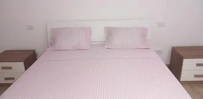 a bed with pink and white sheets and pillows at Rita Apartamento in Mindelo