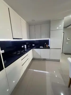 a kitchen with white cabinets and black counter tops at LAGINHA Apartamento in Mindelo