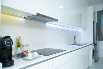 a white kitchen with a sink and a counter top at Apart JC Edificio Victor in Praia