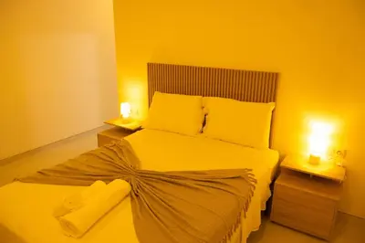 a bedroom with a large bed with two lights on it at Apart JC Edificio Victor in Praia