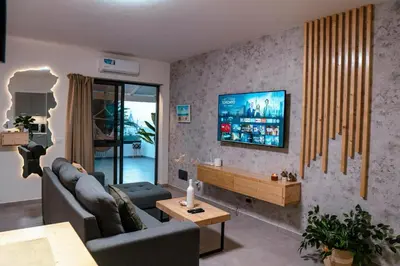 a living room with a couch and a tv on a wall at Tropical Suite 22 A in Santa Maria