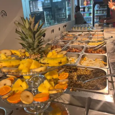 a buffet line with many trays of fruit and food at My Home CV in Praia