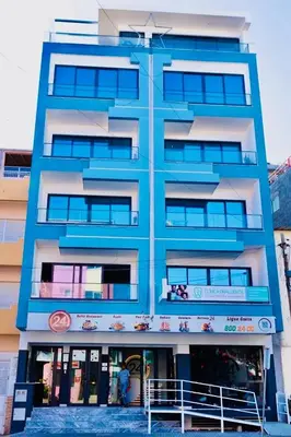 a tall blue building with people standing outside of it at My Home CV in Praia