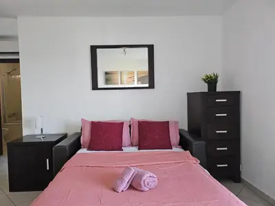a bedroom with a bed with pink sheets and a dresser at Privat Apartment with Pool View! in Santa Maria
