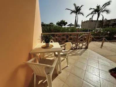 a table and chairs on a balcony with palm trees at Tropical Pool View - By Bobbywashere in Santa Maria