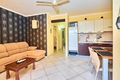 a living room with a couch and a table and a kitchen at Tropical African Vibe in Santa Maria