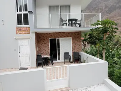 a white house with a balcony with a table at Bentub Home pousada in Ribeira Grande