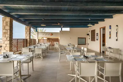 a dining room with tables and chairs and a screen at Barceló Marine Boa Vista - Adults Only in Sal Rei