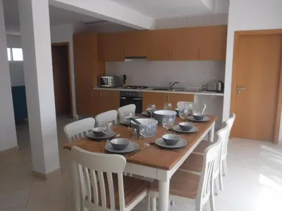 a kitchen with a wooden table and white chairs at Vila Cabral 2 Apartments - AC in Sal Rei
