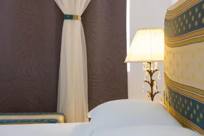 a bedroom with a bed and a lamp and a curtain at Casa kretcheu Mindelo in Mindelo