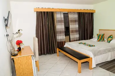 a bedroom with a bed with a bench and a window at LT Aparthotel in Praia