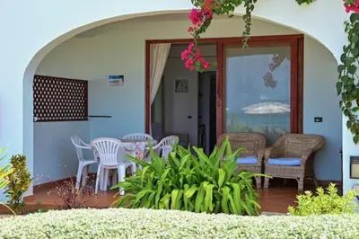 a patio with white chairs and a table with pink flowers at Porto Antigo II Ocean Appartment in Santa Maria