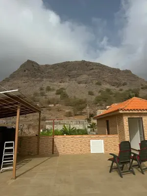 a patio with two chairs and a mountain in the background at Casa Carveiros Panoramic 360 in Tarrafal