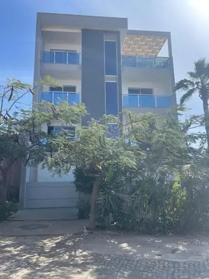 a building with a tree in front of it at Suites Home Tarrafal in Tarrafal