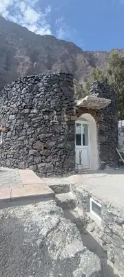 a stone building with a white door and a mountain at Casa Mamã in Portela