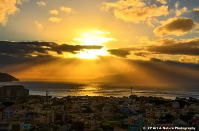 a city with the sun setting over the ocean at Hotel Lazareto in Mindelo