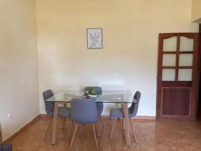 a dining room table with chairs and a clock on the wall at Techas Family Beach Stay 3BR in Central Tarrafal in Tarrafal