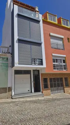 a building with two garage doors on a street at Casa Maré & Museu - Porta Nº 18 in Mindelo