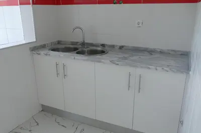 a kitchen with a sink and white cabinets at Magei in Tarrafal