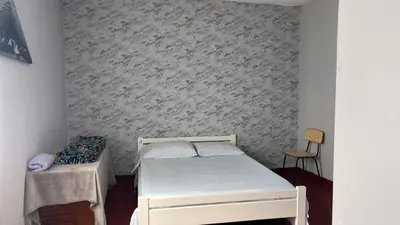 a small bedroom with a white bed and a chair at Pensão Rilda Montrond in Portela